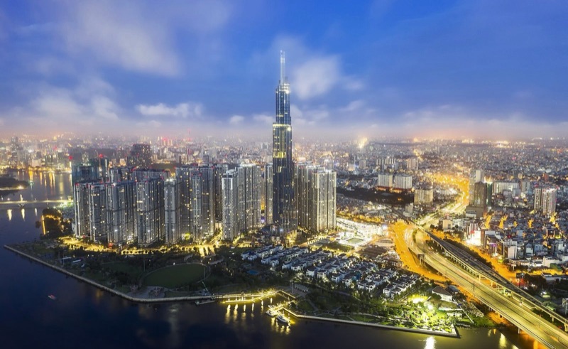 Ảnh chụp từ trên cao tháp Landmark 81 và khu Vinhomes Central Park ven sông Sài Gòn lúc chạng vạng, đường phố lên đèn