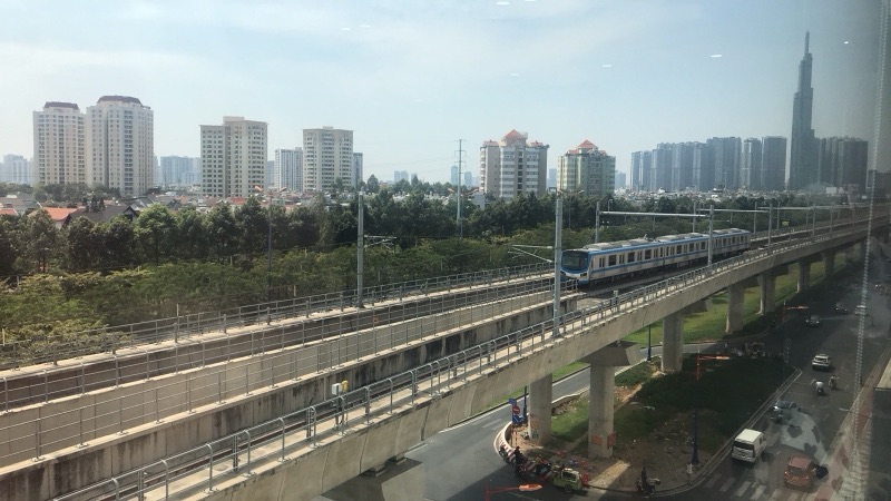 Đoàn tàu metro số 1 chạy trên đường ray trên cao qua Thảo Điền, phía xa là tháp Landmark 81 và các chung cư